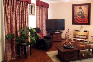 uma sala de estar com uma televisão de ecrã plano e uma cadeira em The Spanish Guesthouse, pets considered em Perth