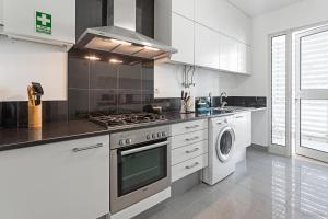 Una cocina con gabinetes blancos y un horno de estufa. en Rodamar I by An Island Apart, en Funchal