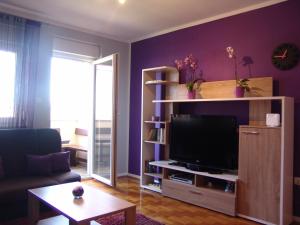 un soggiorno con pareti viola e TV a schermo piatto di Apartment Ines a Medulin