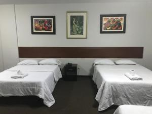 a hotel room with two beds with white sheets at Hospedaje Oscar's in Lima