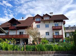 ein großes weißes Gebäude mit braunem Dach in der Unterkunft Haus Friedburg in Velden am Wörthersee