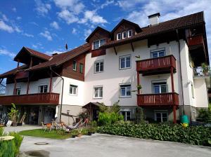 ein großes weißes Gebäude mit Holzbalkonen in der Unterkunft Haus Friedburg in Velden am Wörthersee