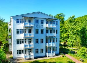 un edificio azul con balcones blancos y árboles en Studio 22 Residenz Seeblick, en Ostseebad Sellin