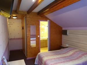 a bedroom with a bed in a room with wooden walls at Auberge Le Moulin Du Plain in Goumois