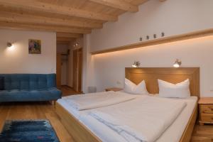 a bedroom with a large bed and a blue couch at Landhaus Charlotte am Geigenbuehel -Apartments in Seefeld in Tirol