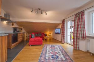 a living room with a red couch and a kitchen at Landhaus Charlotte am Geigenbuehel -Apartments in Seefeld in Tirol