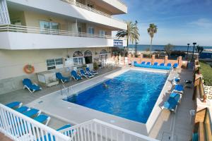 a pool at a hotel with blue chairs and the ocean at Sea Star in Fuengirola