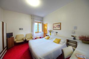 a hotel room with a large white bed and chairs at Grand Hotel Milano in Chianciano Terme