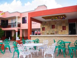 un groupe de chaises vertes et une table devant un bâtiment dans l'établissement Hotel Hacienda Cortes, à Mérida