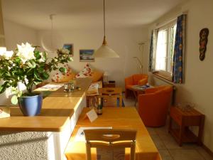 ein Wohnzimmer mit Tischen und orangefarbenen Stühlen in der Unterkunft Haus Abendberg in Wilderswil