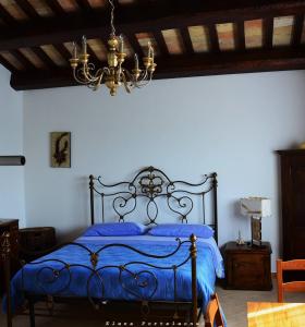 Schlafzimmer mit einem blauen Bett und einem Kronleuchter in der Unterkunft Casale il Cerqueto in San Severino Marche