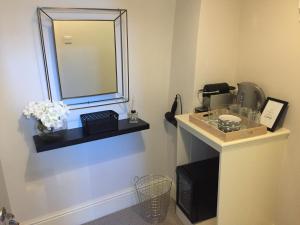 a bathroom with a mirror and a counter with flowers at Pen y Bryn in Conwy