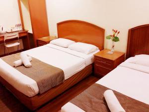 a hotel room with two beds with white sheets at SkyGlobal Hotel in Labuan