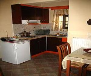 a kitchen with brown cabinets and a table with a tableablish at Pension Stella in Naxos Chora