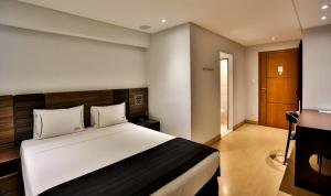 um quarto com uma grande cama branca num quarto em Palais Hotel em São Vicente
