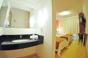 a bathroom with a sink and a bed in a room at Hotel Aguadero in Passo Fundo