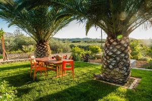 a table and chairs sitting under two palm trees at Aloni Home in Petrokefálion