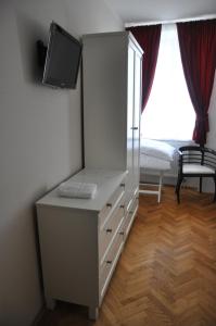 ein Schlafzimmer mit einer Kommode, einem TV und einem Bett in der Unterkunft Pivovar Hotel Na Rychtě in Ústí nad Labem