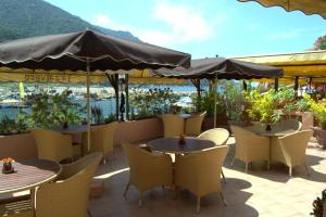 eine Terrasse mit Tischen, Stühlen und einem Sonnenschirm in der Unterkunft La Calypso in Porto Ota