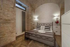 ローマにあるWhite flat Rione Montiのレンガの壁、ベッド付きのベッドルーム1室