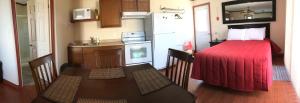 a small kitchen with a red bed in a small room at Motel Sainte-Flavie in Sainte-Flavie