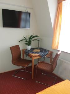 Habitación con mesa, 2 sillas y TV. en Gästehaus Loschwitz, en Dresden