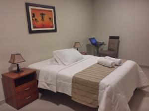 a bedroom with a bed and a chair with a laptop on it at PiscoMar Peru in Pisco +64 photos