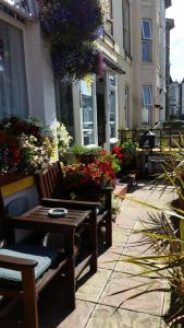 a wooden bench sitting next to a building with flowers at Sunnyside Hotel in Great Yarmouth