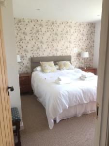 ヘイルシャムにあるWest Lodge B&Bの花柄の壁紙を用いた白いベッドが備わるベッドルーム1室