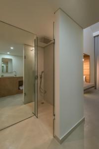 a glass door in a room with a shower at Bitzaro Grande Hotel & Suites in Kalamaki