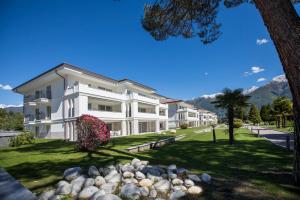 ein großes weißes Gebäude mit Bergen im Hintergrund in der Unterkunft Delta Resort Apartments in Ascona