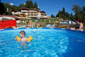 un jeune garçon dans une piscine avec deux jouets dans l'établissement Hotel Berghof, à Söll
