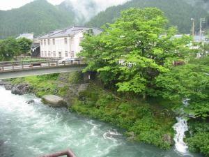 un ponte su un fiume con cascata di Miharaya Ryokan a Gujo