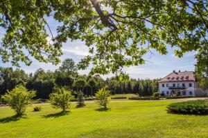 a large white house in a field with trees at Šubrakkrasti in Vestiena