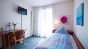 a bedroom with a bed and a desk and a window at Hotel Schloss Romanshorn in Romanshorn