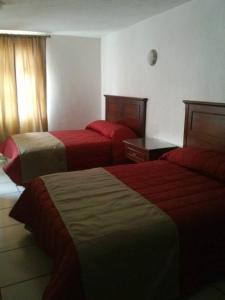 Cette chambre d'hôtel comprend 2 lits avec des draps rouges. dans l'établissement Hotel El Beso De Calixto, à Guanajuato