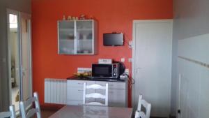 a kitchen with orange walls and a table with a microwave at Chambres climatisées petits déjeuners compris in Aussonne