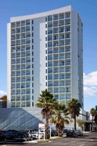 a tall building with palm trees in front of it at Proximity Apartments Manukau / Auckland Airport in Auckland