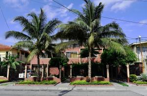 瓜亞基爾的住宿－Hostel Nucapacha，两棵棕榈树,在一座粉红色的建筑前