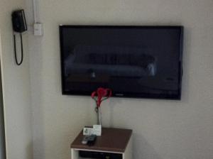 a television on a wall with a vase on a table at Mollymook Paradise Haven Motel in Mollymook