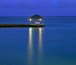 a couple sitting on a island in the water at night at The Warwick Fiji in Korolevu