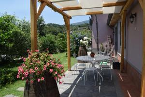 un patio con mesa, sillas y flores en Le Case Di Bacco, en Santa Venerina