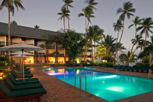 a hotel with a pool and palm trees at night at The Warwick Fiji in Korolevu