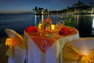 a table with two chairs and a table with wine glasses at The Warwick Fiji in Korolevu