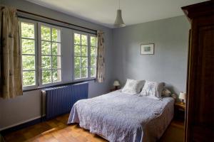 a bedroom with a bed and two windows at Le Pré Sainte-Anne in Offranville
