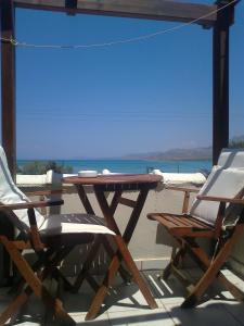 einen Tisch und Stühle auf einer Terrasse mit Meerblick in der Unterkunft Kontogoni Rooms in Elafonisos