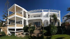 una casa blanca con una escalera delante en Villa Nora, en Moulay Bousselham