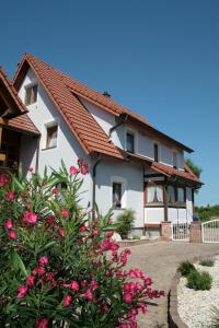 uma casa branca com um telhado vermelho e flores cor-de-rosa em Odas Feriendomizil em Kappel-Grafenhausen