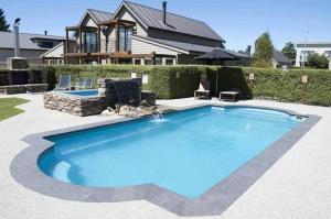 a large blue swimming pool in front of a house at Lansdown Apartments in Wanaka