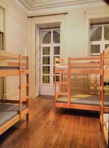 een kamer met 3 stapelbedden en een deur bij Dans L'Atelier Hostel Unidade Porta Nova in Braga